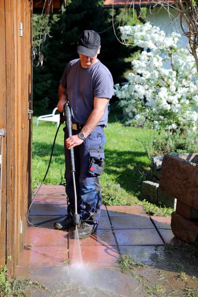 Janitorial service, cleaning of stones in the garden with the high-pressure cleaner.